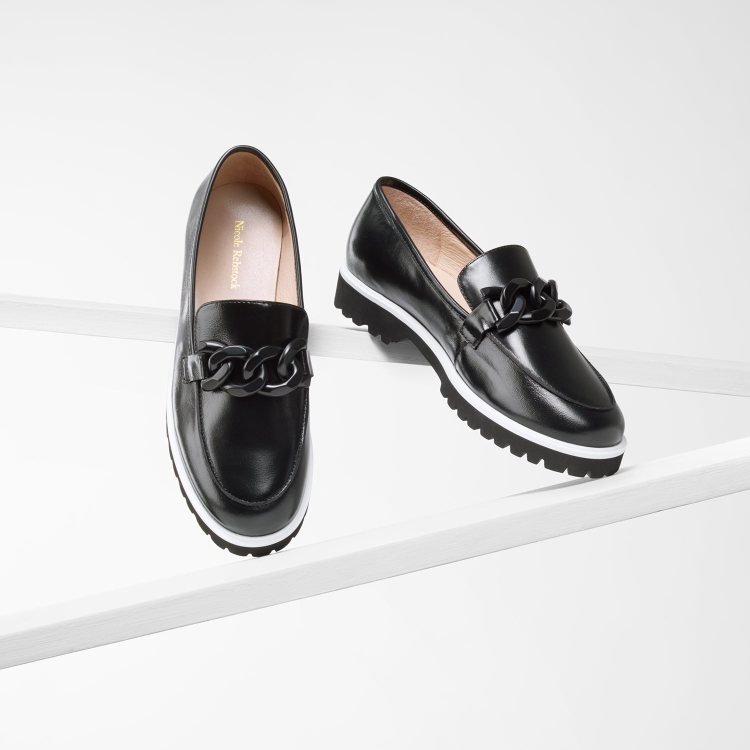 Dominica black oil loafer on plank showing all angles with white rand and black chain detail.